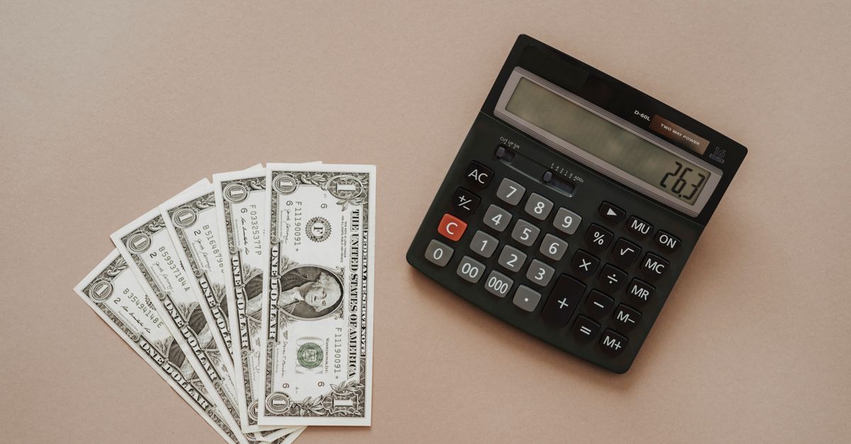 A calculator displaying '26.3' beside four one-dollar bills on a beige background.
